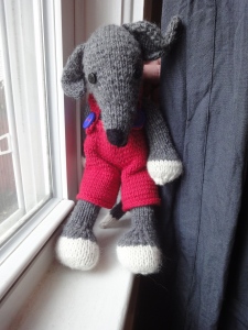 Greyhound doll in red overalls with blue buttons